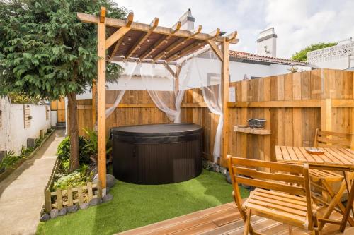 a garden with a pergola and a table and bench at Cozy home with jacuzzi - near the airport in Ponta Delgada
