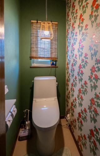 a bathroom with a toilet with a flowery wallpaper at sukeemon in Biei