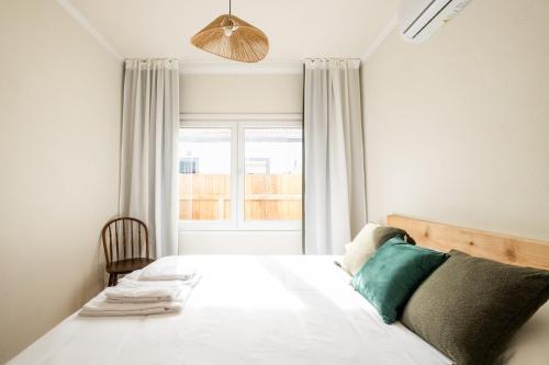 a bedroom with a large white bed with a window at Cozy home with jacuzzi - near the airport in Ponta Delgada