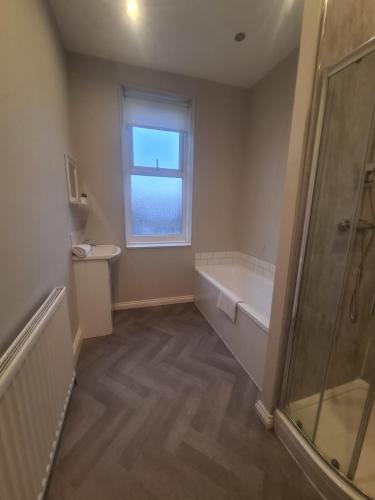 a bathroom with a bath tub and a window at AA Exec Apartments in South Shields