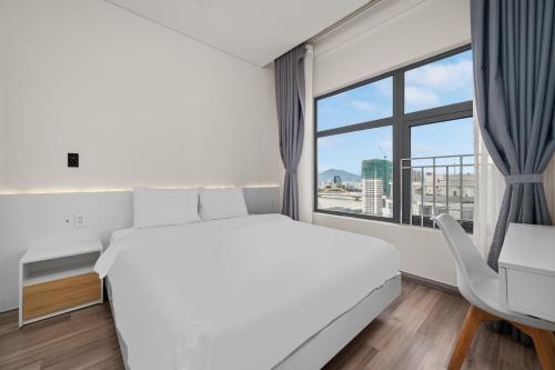 a bedroom with a large white bed and a window at Monarchy Riverside Da Nang - Modern Stay & Pool in Da Nang