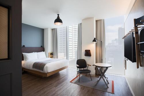 a hotel room with a bed and a desk and a chair at MOXY Osaka Honmachi in Osaka