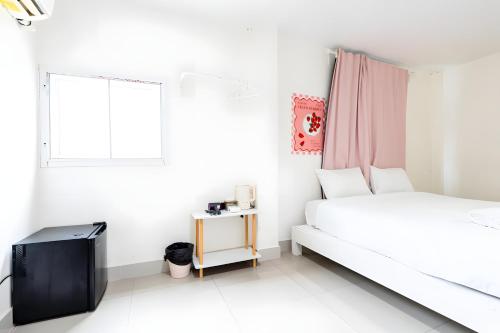 a white bedroom with a bed and a window at Oh My Naptel Nana Soi 3 -โอมาย แนปเทล ซอย 3 in Makkasan