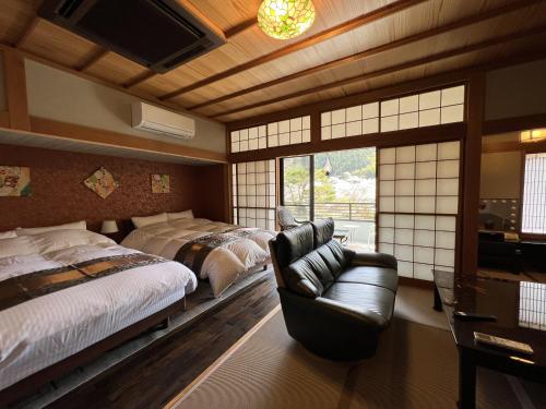a bedroom with two beds and a couch and a television at すいこうえんさくら in Fujinomiya