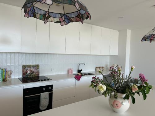 een keuken met witte kasten en een vaas met bloemen bij Elite Stay Ladies Only in Port Macquarie