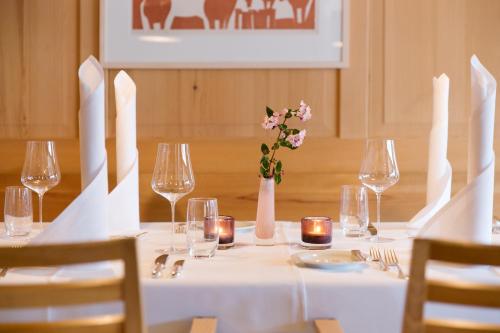 a white table with glasses and a vase with flowers at Krone Hittisau - Hotel & Restaurant im Bregenzerwald in Hittisau
