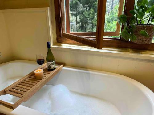 a bath tub with a bottle of wine and a glass at Coral Fern Retreat in Forrest