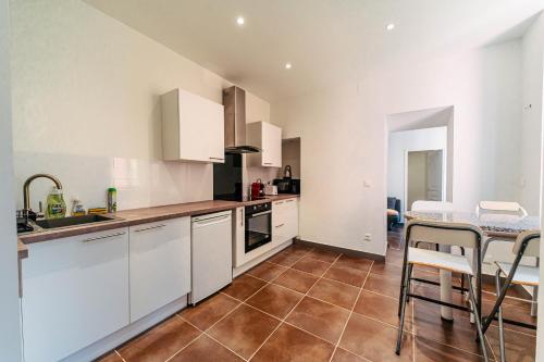 a kitchen with white cabinets and a table and chairs at Cocoon Bleu T2 Cosy Gare et Centre à Pied in Fréjus