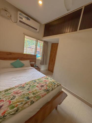 a bedroom with a bed with a floral bedspread at Nadhi Mane River-front Beach Stay in Tadri