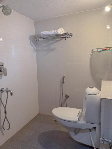 a bathroom with a white toilet and a shower at Nadhi Mane River-front Beach Stay in Tadri