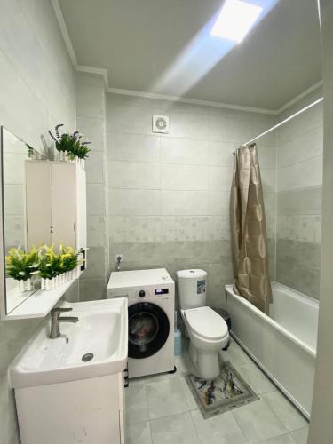 a bathroom with a washing machine next to a toilet at Jk SHANYRAK in Shymkent