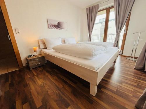 a bedroom with a large white bed with a wooden floor at Apart Spieljochbahn in Fügenberg