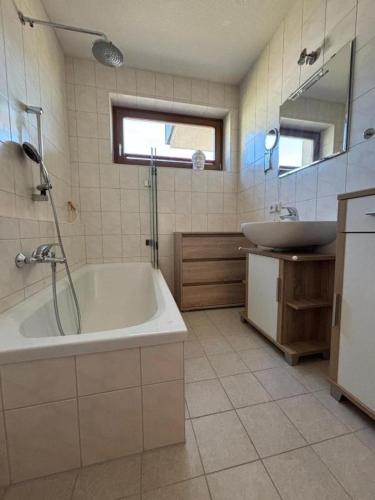 a bathroom with a tub and a sink at Apart Spieljochbahn in Fügenberg