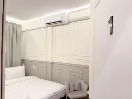 a white bedroom with two beds and a chair at CASA Sukhumvit XI -ซอยสุขุมวิท 11 in Makkasan