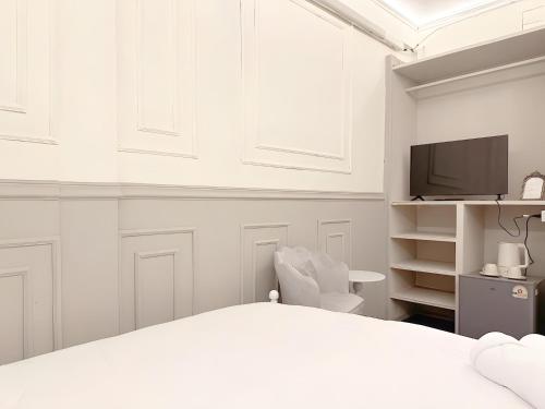 a white bedroom with a bed and a tv at CASA Sukhumvit XI -ซอยสุขุมวิท 11 in Makkasan