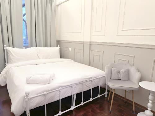 a white bedroom with a bed and a chair at CASA Sukhumvit XI -ซอยสุขุมวิท 11 in Makkasan