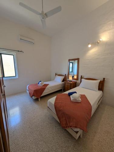 a bedroom with two beds and a ceiling fan at Gozitan Charm in Xaghra with Pool in Xagħra
