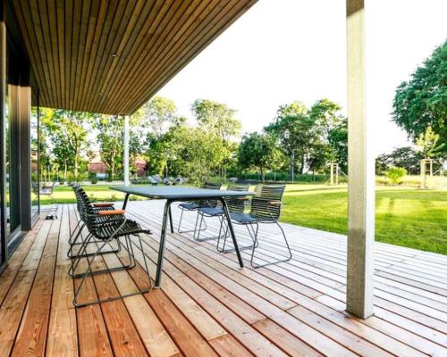 a patio with a table and chairs on a deck at Nordic Bliss Cozy Villa with Jacuzzi & Sauna in Nørdstebø 