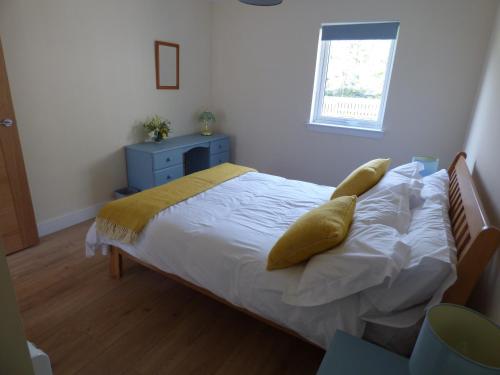 a bedroom with a bed with white sheets and yellow pillows at Taigh Coig in Gairloch