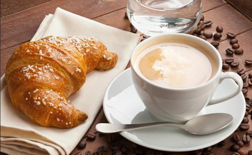 una tazza di caffè e un cornetto su un tavolo di B&B Buon Cammino Tuscia - Parcheggio - convenzionato con impianti termali a Viterbo