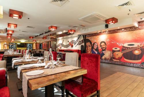 a restaurant with red chairs and a mural of two women at Howard Johnson Bur Dubai in Dubai