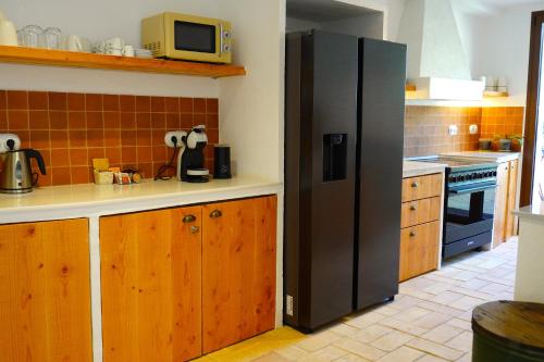 a kitchen with a black refrigerator and wooden cabinets at Ses Terrisses Hotel in Palafrugell
