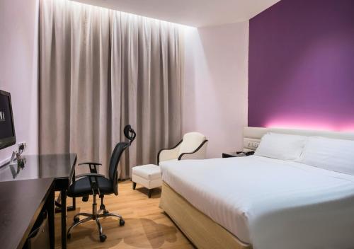 a hotel room with a bed and a desk and chair at Furama City Centre in Singapore