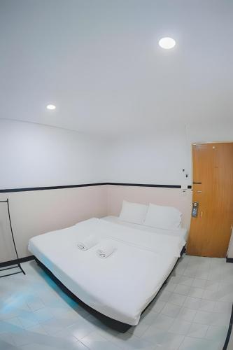 a white bed in a room with a wooden door at xx Mitr Inn - Phuket Old Town มิตรอินน์ ภูเก็ต เมืองเก่า 3 in Phuket