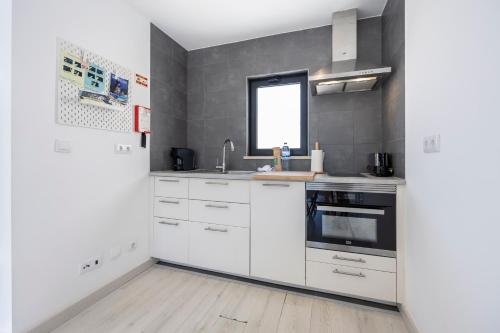 une cuisine avec des armoires blanches et une fenêtre dans l'établissement Villa Jump Jibe, à Sagres