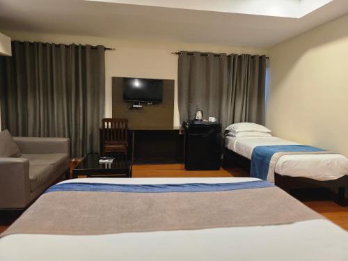 a hotel room with two beds and a couch at MG Beatle Hotel Tirupati in Tirupati