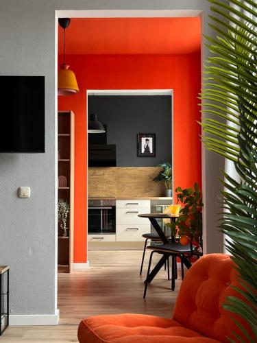a kitchen with orange walls and a dining room at K2-Project - Kleines Loft beim Schlossteich in Chemnitz