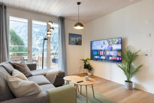 a living room with a couch and a tv on a wall at Scenic Holiday Apartment with Balcony Views in Lungern