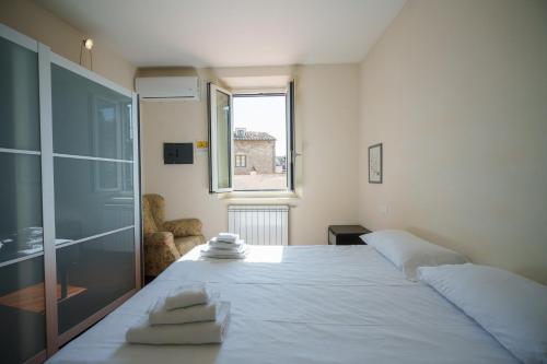 ein Schlafzimmer mit einem großen weißen Bett mit einem Fenster in der Unterkunft Anguillara in the Heart of Florence in Florenz