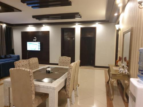 une salle à manger avec une table et des chaises et une télévision dans l'établissement Royal Villa Islamabad, à Islamabad