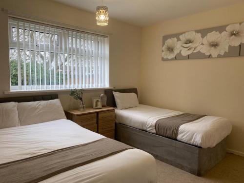 1 dormitorio con 2 camas y una ventana con flores en la pared en Durham Stay 2BR, en Durham