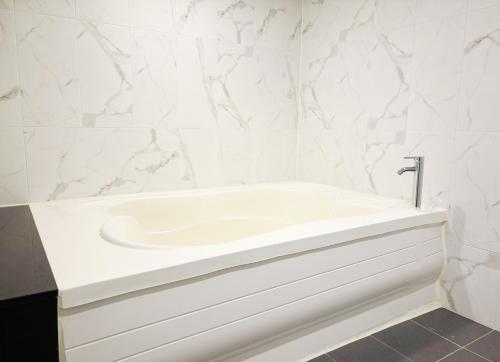 a white bath tub in a bathroom with marble walls at Signature Tourist Hotel in Seoul