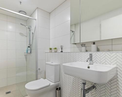 a white bathroom with a toilet and a sink at Luxury apartment with Brindabella views in Tuggeranong