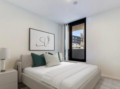 a white bedroom with a large bed and a window at Luxury apartment with Brindabella views in Tuggeranong