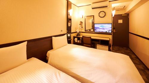 a room with two beds and a desk with a television at Toyoko Inn Maibara eki Shinkansen Nishi guchi in Maibara