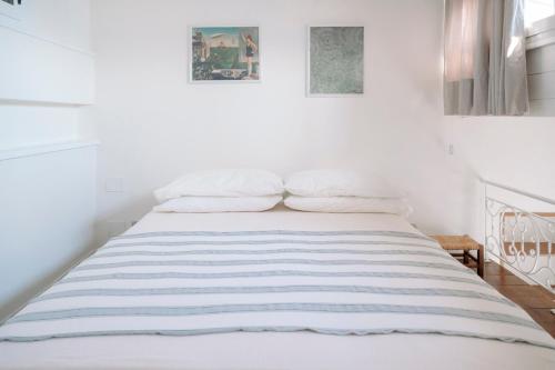 a bed in a white room with two pictures on the wall at Radici 1937 - Lodge sul mare in Scilla
