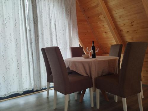 a dining room table with chairs and a bottle of wine at Pax Montana in Blidinje