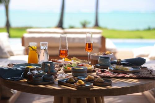 una mesa con comida y dos copas de vino en Origem Patacho Design Hotel, en Porto de Pedras