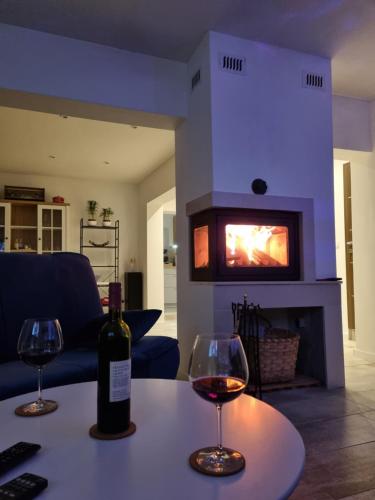 two glasses of wine on a table in front of a fireplace at Cosy home D&D in Brod Moravice