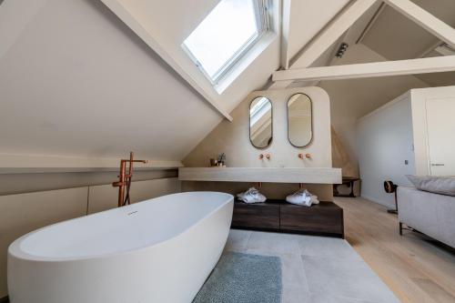 オーステンデにあるVilla Euphrosina boutique verblijf met verwarmd zwembad, sauna, vlakbij het strand van Oostendeの屋根裏に白い大型バスタブ付きのバスルーム