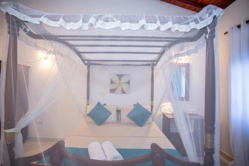 a bedroom with a canopy bed with blue pillows at Su Yu villa in Unawatuna