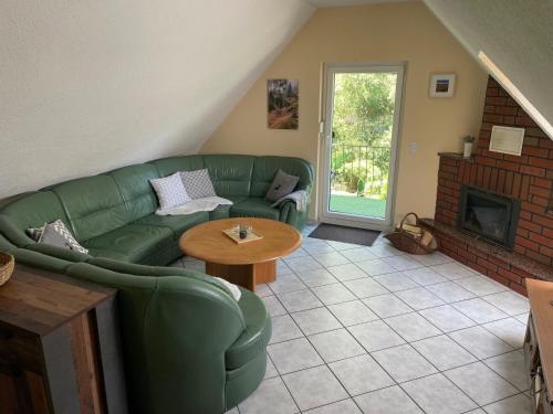 - un salon avec un canapé vert et une cheminée dans l'établissement Ferienhaus in Elend, à Elend