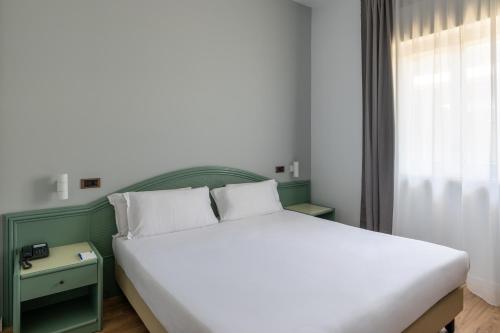 a bedroom with a white bed with a green headboard at Hotel Riva Del Sole in Giovinazzo