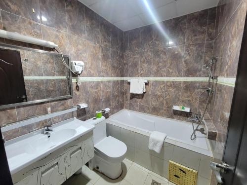 a bathroom with a tub and a toilet and a sink at Safyad Hotel in Yaoundé