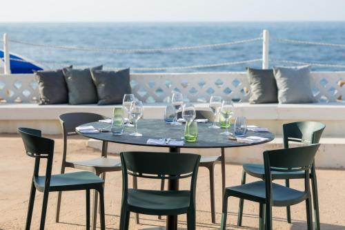 a table with chairs and wine glasses on the beach at Hotel Riva Del Sole in Giovinazzo