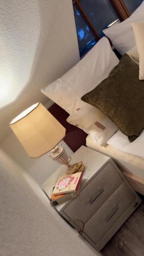 a lamp and a book on a nightstand next to a bed at Gabriel in Sankt Augustin